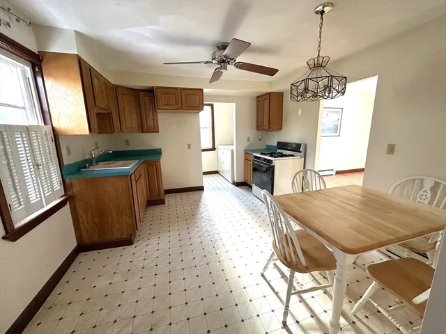 a kitchen with stainless steel appliances a stove a refrigerator a sink a dining table and chairs with wooden floor