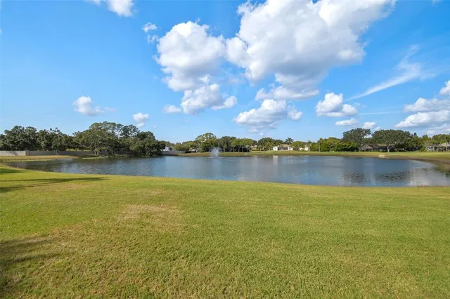 a view of a large pool with lawn chairs under an umbrella