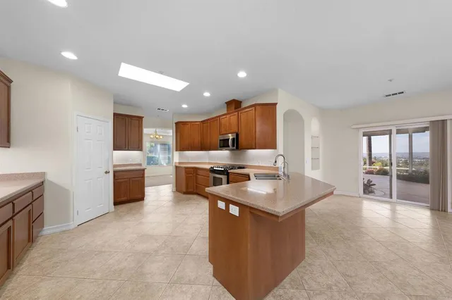 a large kitchen with stainless steel appliances kitchen island granite countertop a large counter top and a stove top oven