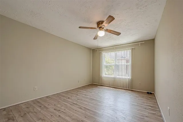 an empty room with wooden floor and ceiling fan