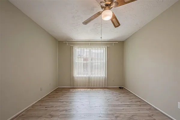 an empty room with wooden floor fan and windows