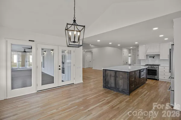 a view of kitchen with granite countertop stainless steel appliances cabinets a wooden floor and a chandelier