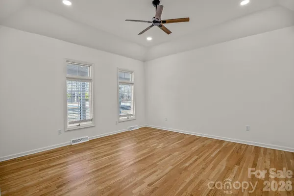 a view of empty room with wooden floor and fan