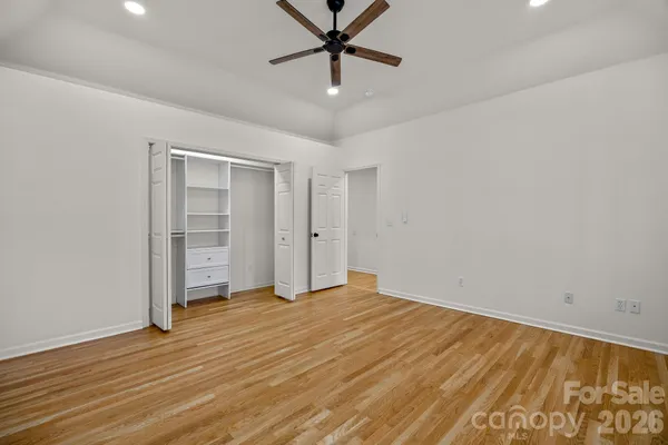 a view of a room with wooden floor and a ceiling fan