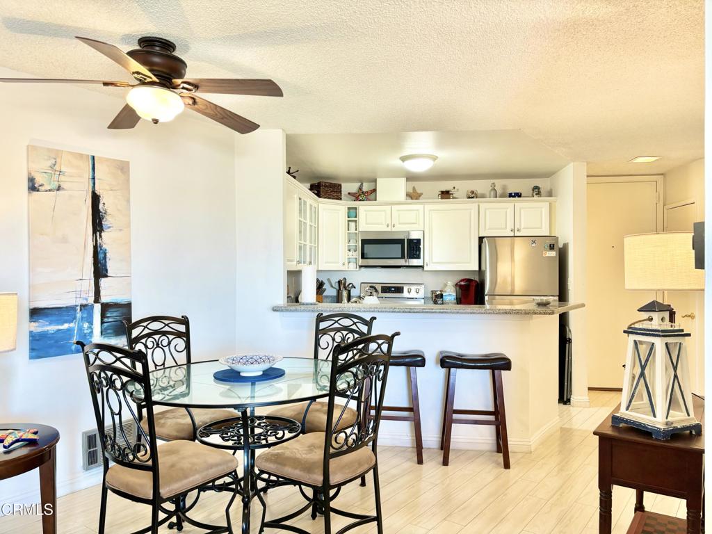 3101 Peninsula Road, Unit 312 Oxnard, CA 93035 - Photo 3 of 38 a kitchen with stainless steel appliances kitchen island granite countertop a dining table chairs and white cabinets
