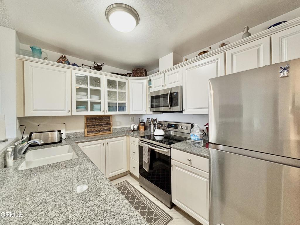 3101 Peninsula Road, Unit 312 Oxnard, CA 93035 - Photo 9 of 38 a kitchen with stainless steel appliances granite countertop a refrigerator sink stove microwave and cabinets