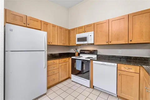 a kitchen with stainless steel appliances granite countertop a refrigerator sink stove and white cabinets