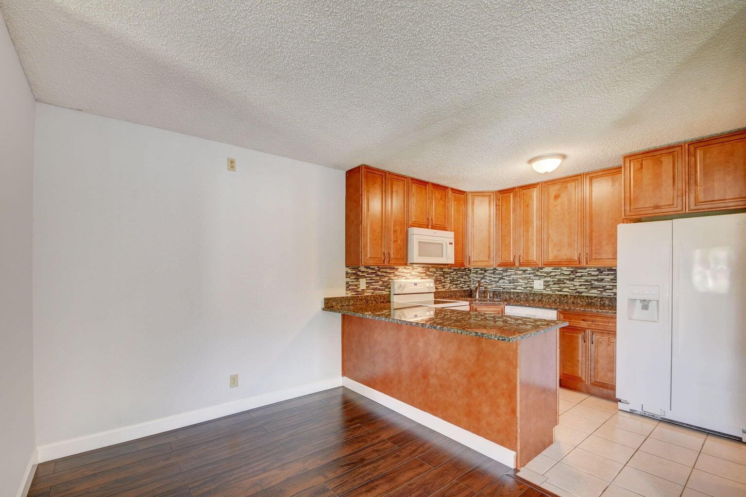 4844 Sable Pine Circle, Unit D2 West Palm Beach, FL 33417 - Photo 12 of 45 a kitchen with stainless steel appliances granite countertop a stove a refrigerator and a refrigerator