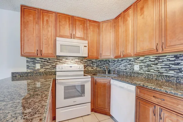 a kitchen with granite countertop stainless steel appliances a stove a sink and a microwave