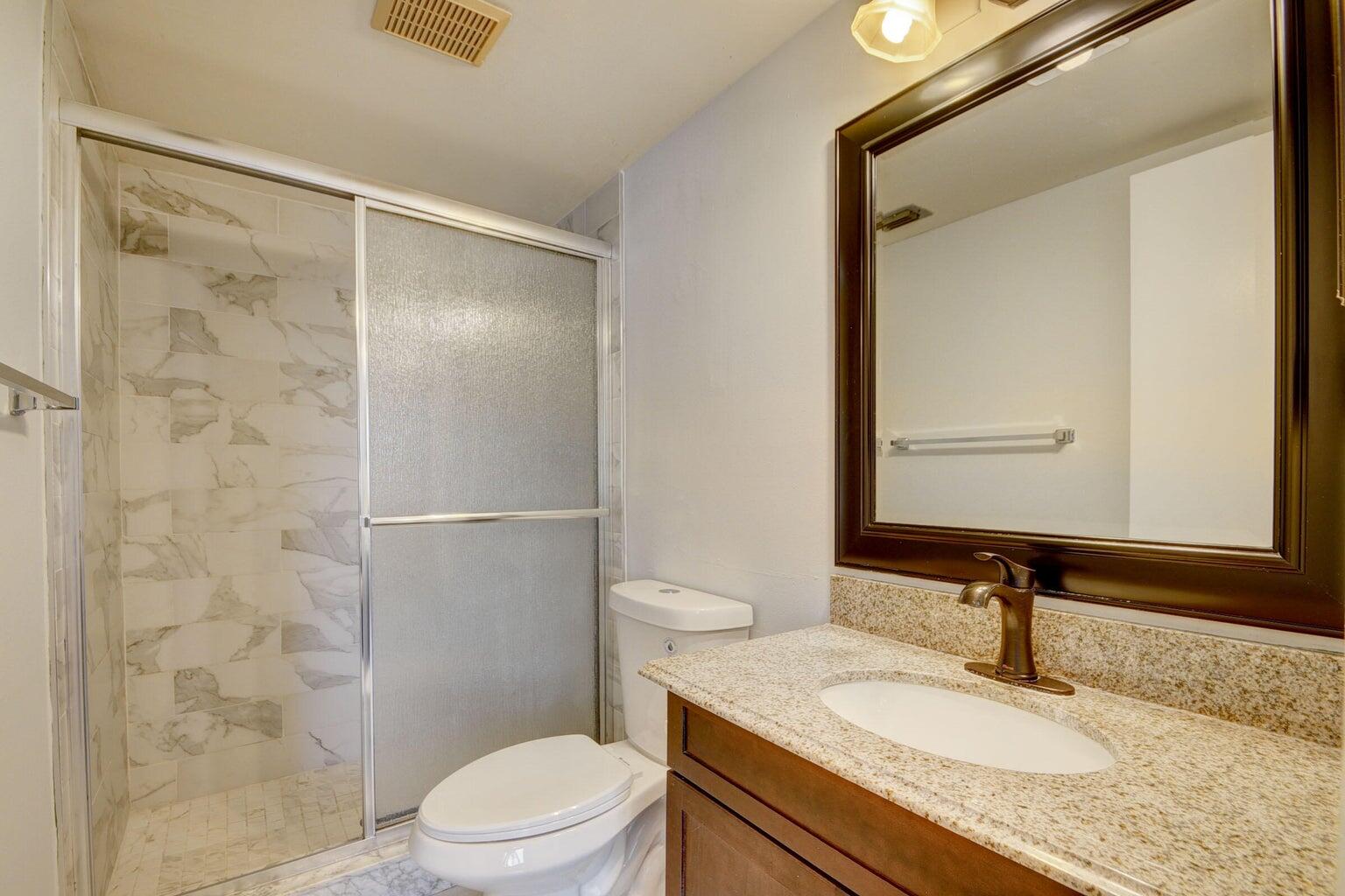 4844 Sable Pine Circle, Unit D2 West Palm Beach, FL 33417 - Photo 21 of 45 a bathroom with a granite countertop sink toilet and shower