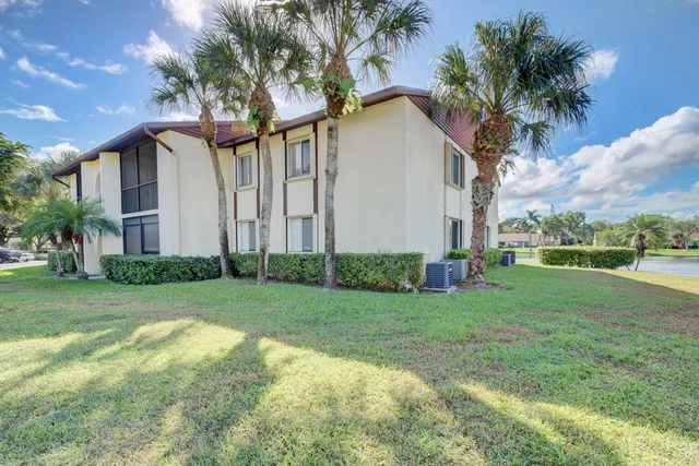 a view of a white house next to a yard with palm trees