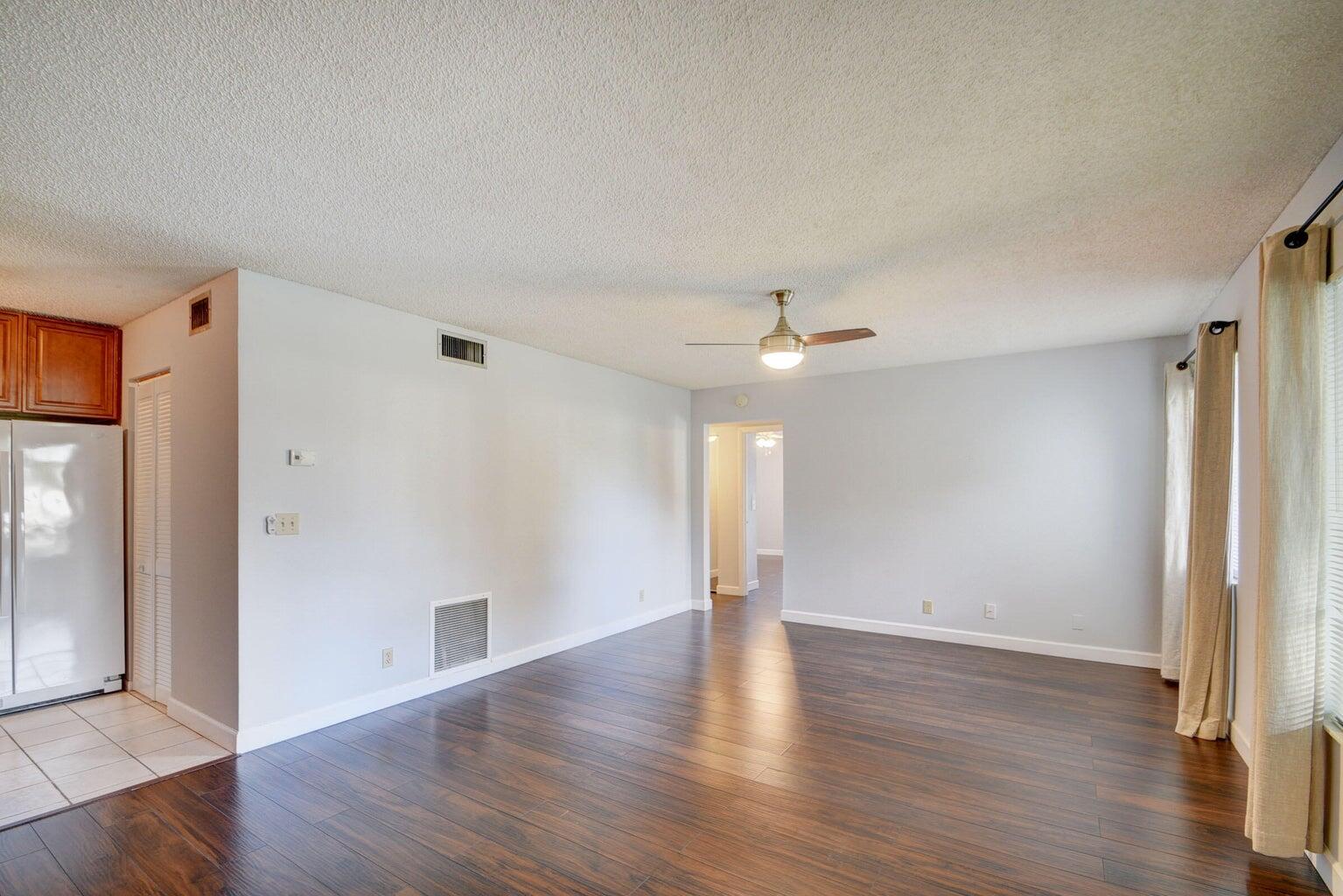 4844 Sable Pine Circle, Unit D2 West Palm Beach, FL 33417 - Photo 8 of 45 an empty room with wooden floor ceiling fan and windows