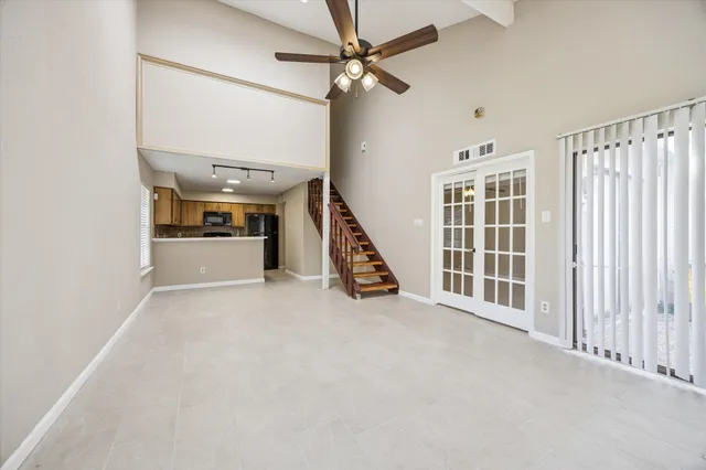 an empty room with windows and a ceiling fan