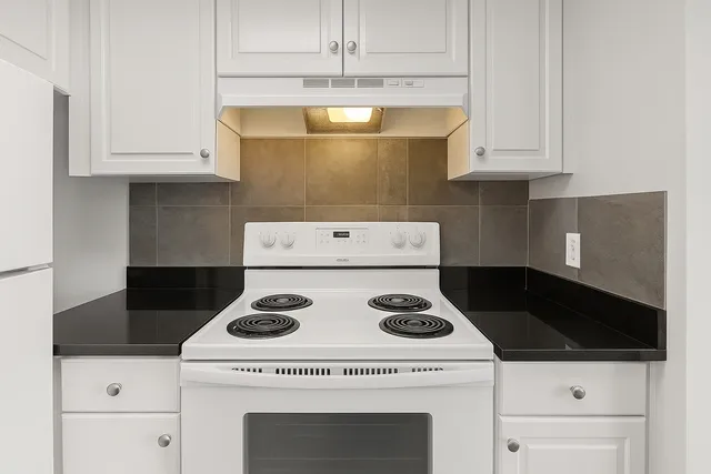 a kitchen with a stove and white cabinets
