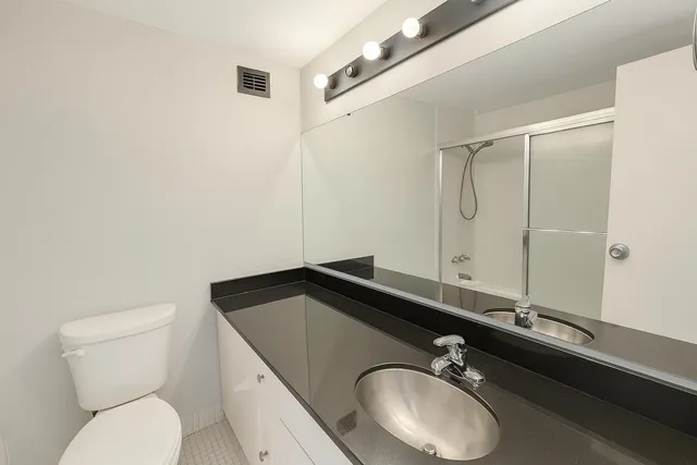 a bathroom with a granite countertop sink a toilet and a mirror