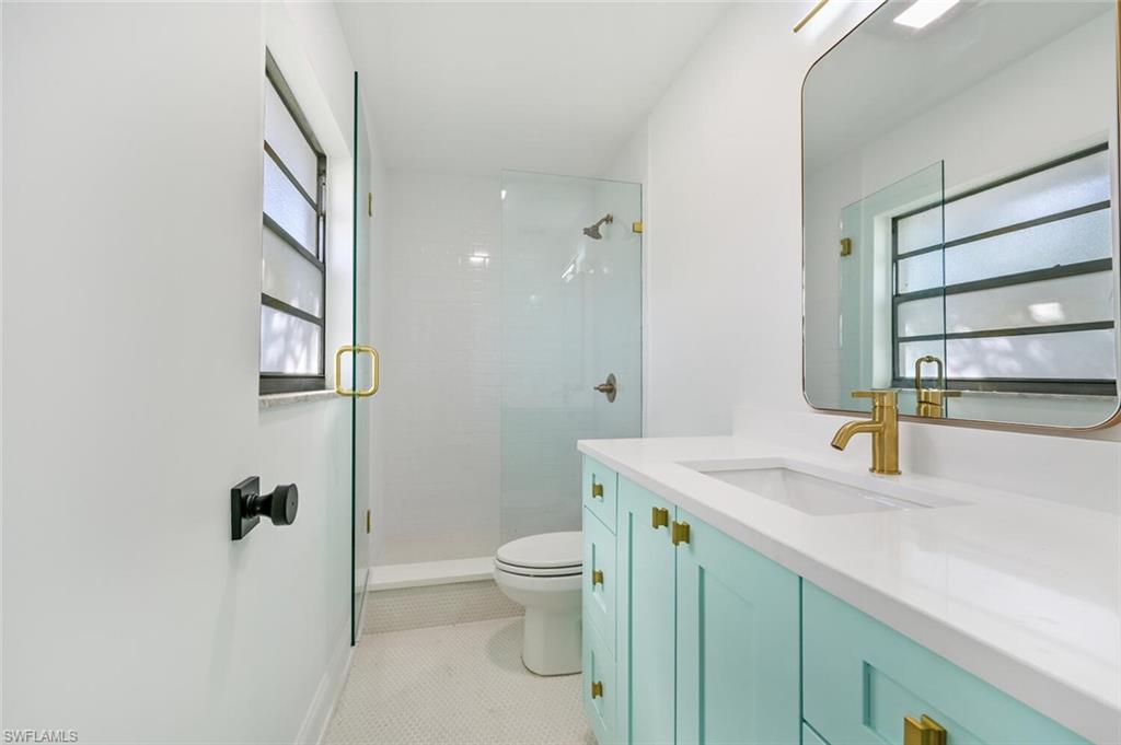 4666 Dorando Drive Naples, FL 34103 - Photo 18 of 30 a bathroom with a granite countertop toilet sink and mirror