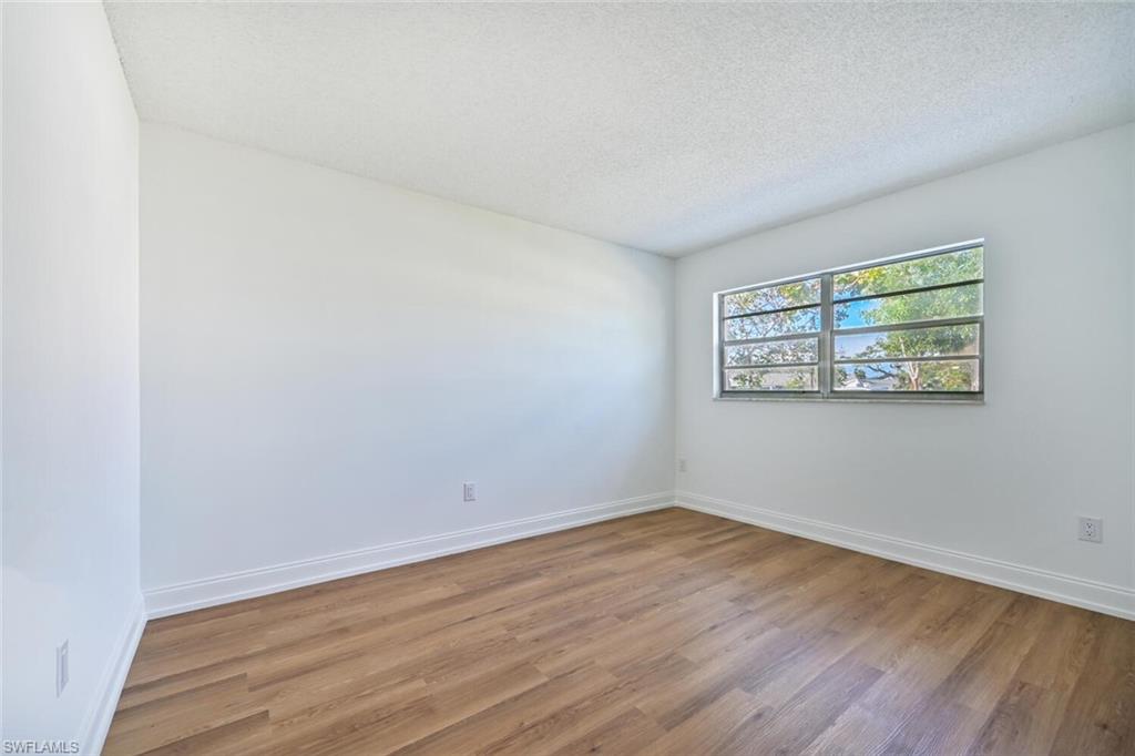 4666 Dorando Drive Naples, FL 34103 - Photo 19 of 30 an empty room with wooden floor and windows