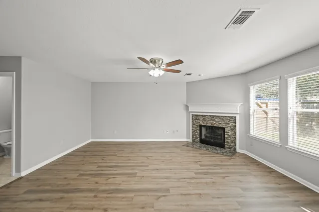 a view of an empty room with wooden floor fireplace and a window