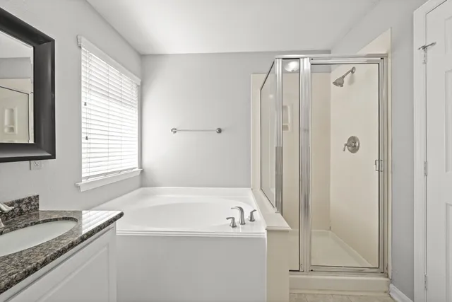 a bathroom with a granite countertop tub sink and mirror