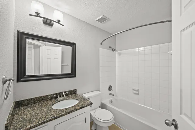 a bathroom with a granite countertop sink toilet a mirror and shower