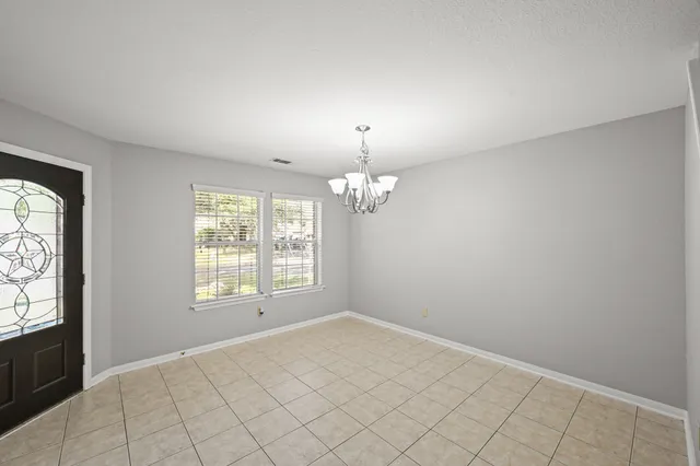 an empty room with chandelier fan and windows