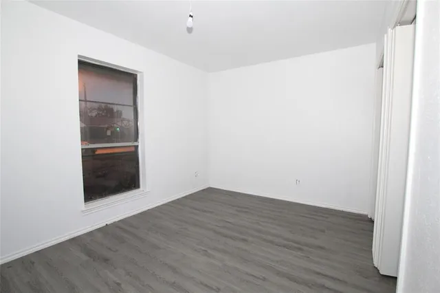 a view of an empty room with wooden floor and closet