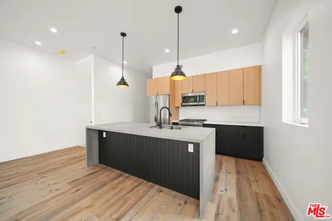 a kitchen with kitchen island a sink a stove and wooden floor