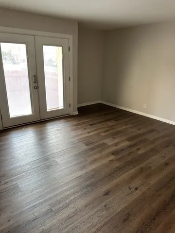 a view of an empty room with wooden floor and window