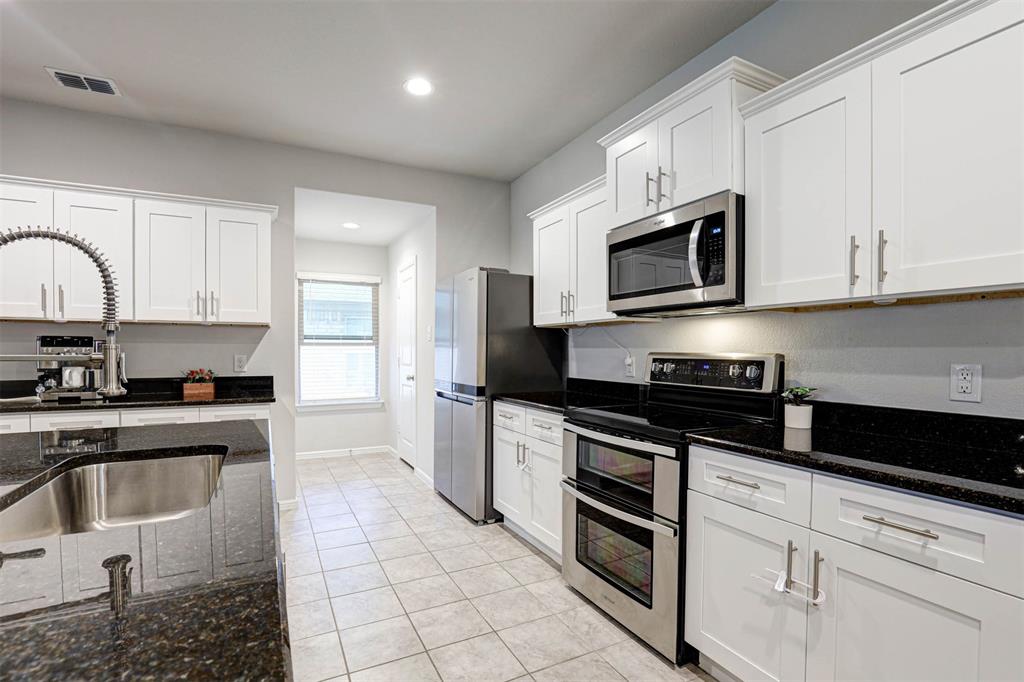 512 Amory Street Azle, TX 76020 - Photo 4 of 25 a kitchen with stainless steel appliances granite countertop grey cabinets a stove a sink and dishwasher