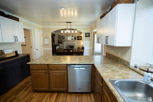 7532 North Castle Rock Road Eagle Mountain, UT 84005 - Photo 5 of 40 Kitchen featuring dishwasher, a fireplace, a peninsula, crown molding, and light countertops