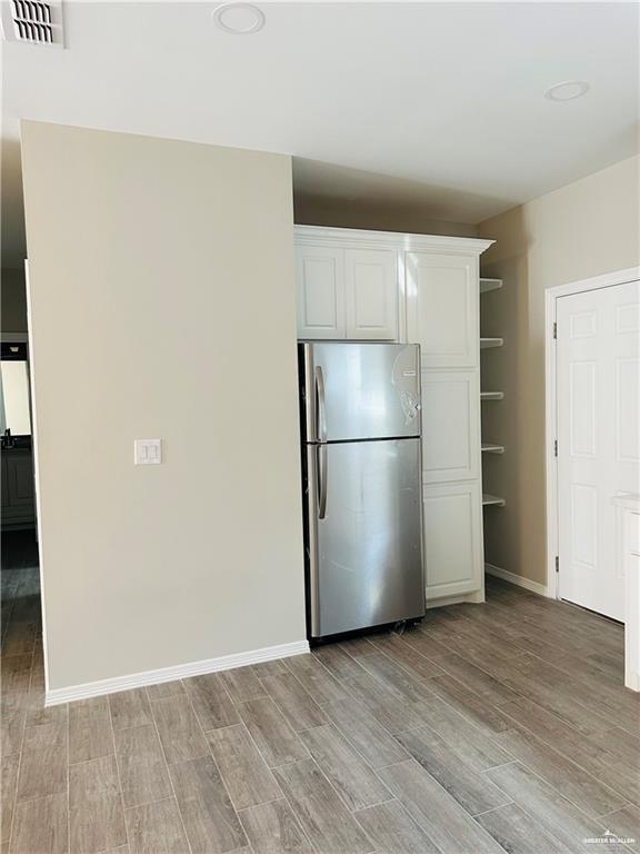 1614 Playa Drive, Unit 3 Weslaco, TX 78596 - Photo 3 of 11 a view of a refrigerator in kitchen and an empty room with wooden floor