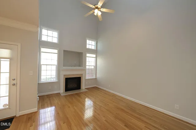 an empty room with wooden floor fireplace and windows