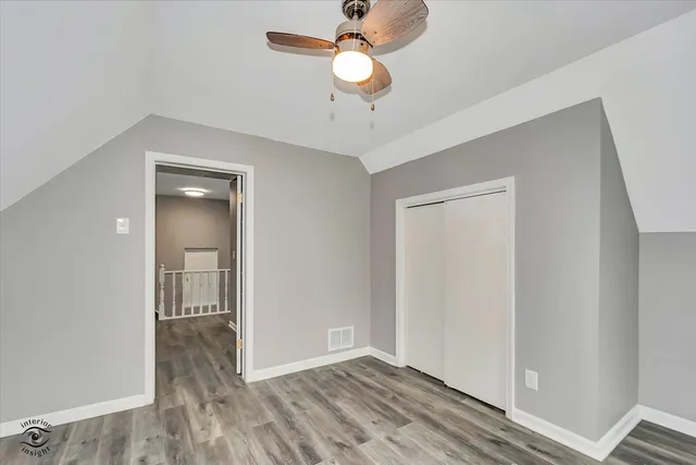a view of an empty room and chandelier fan and wooden floor