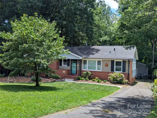 a front view of a house with a garden and trees