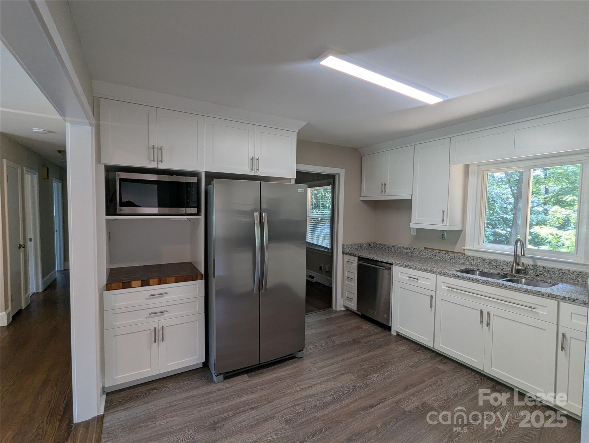 1614 Keeling Place Charlotte, NC 28210 - Photo 3 of 17 a kitchen with stainless steel appliances granite countertop a refrigerator a sink a stove and white cabinets with wooden floor