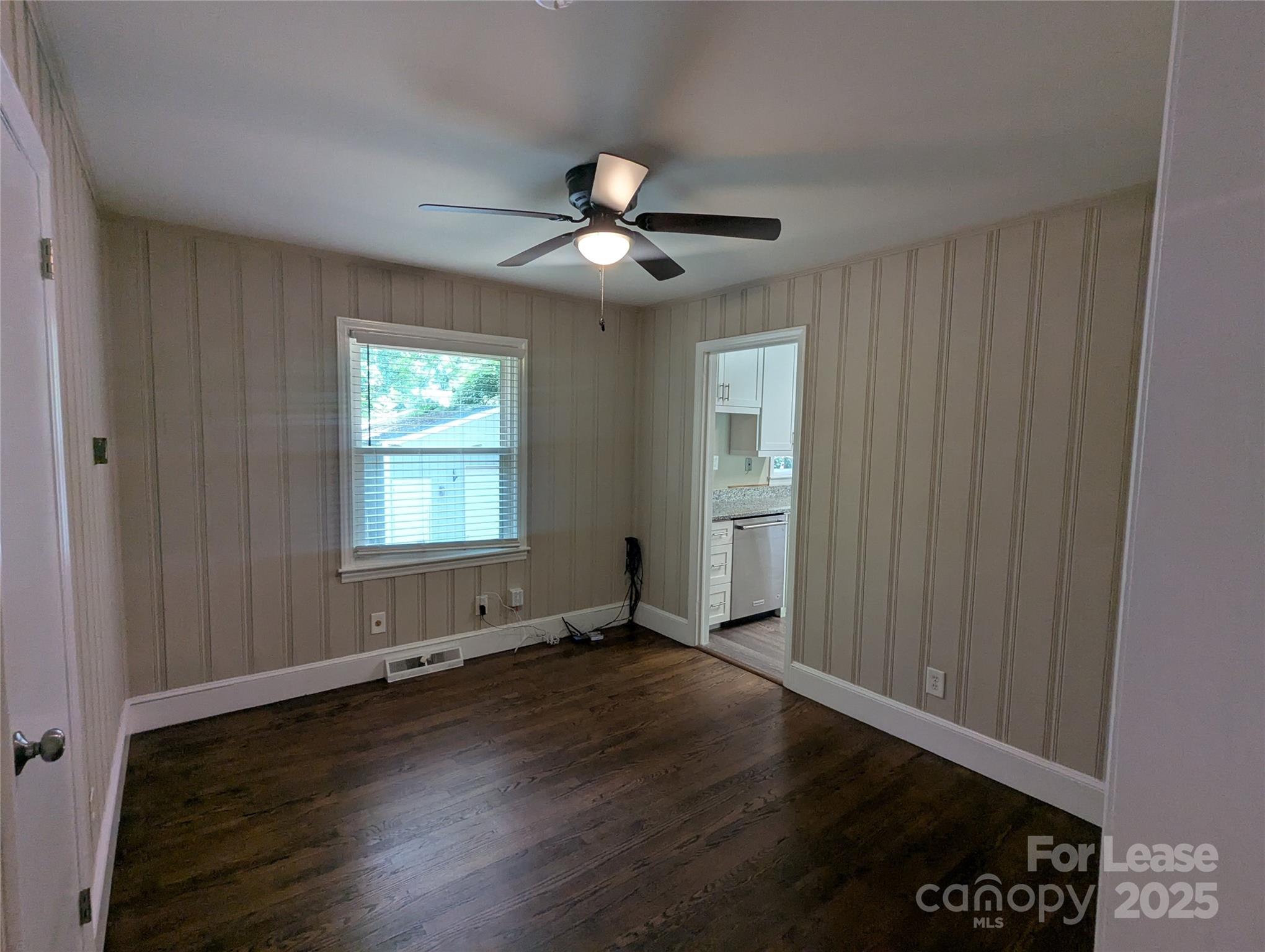 1614 Keeling Place Charlotte, NC 28210 - Photo 6 of 17 an empty room with wooden floor chandelier fan and windows