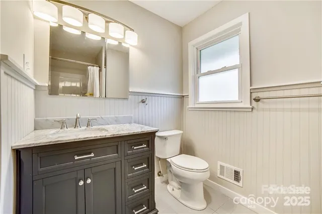 a bathroom with a granite countertop toilet a sink a mirror and a window