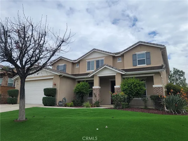 a front view of a house with a garden and trees