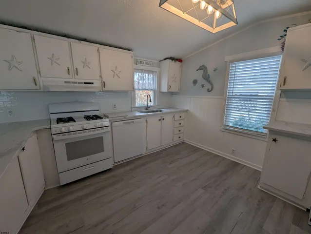 a kitchen with granite countertop white cabinets and white appliances
