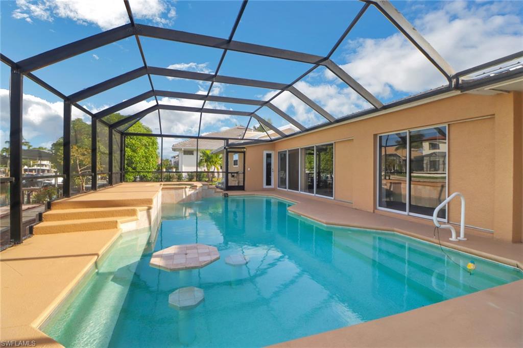 562 Goldcoast Court Marco Island, FL 34145 - Photo 20 of 28 a view of a backyard with table and chairs under an umbrella