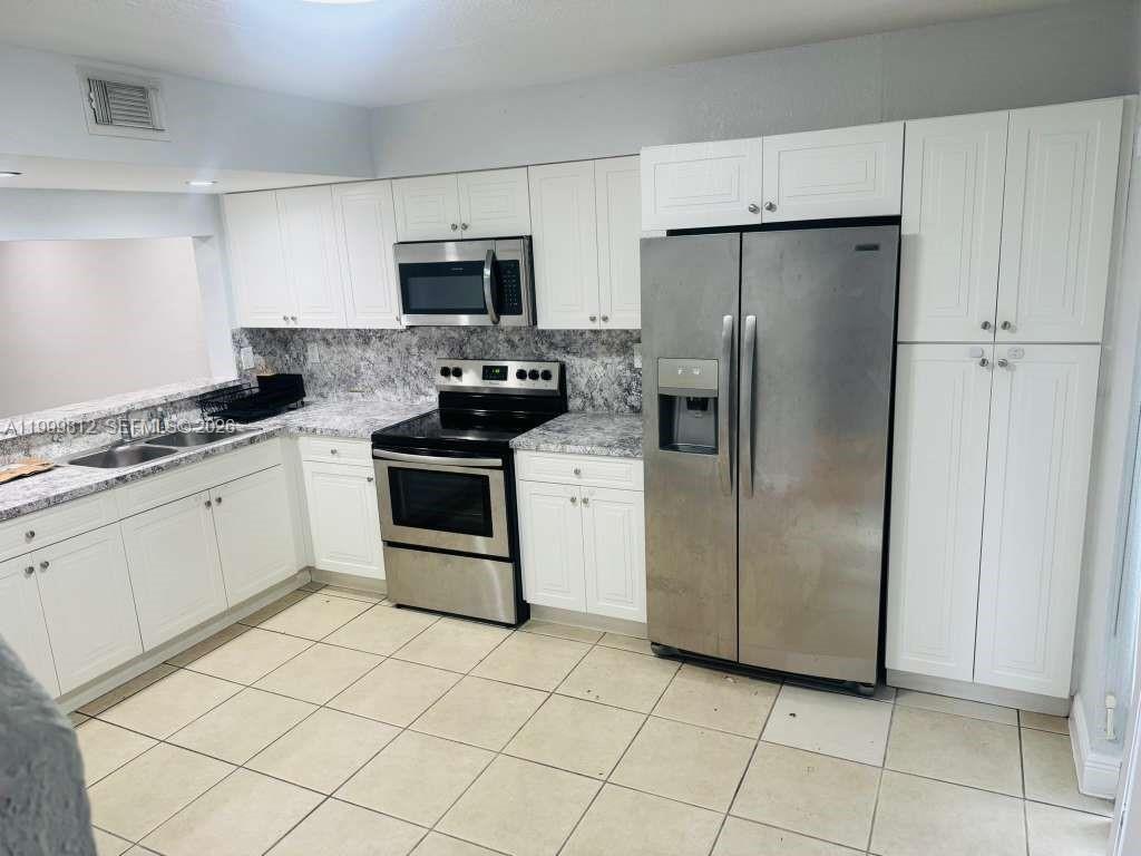8270 Southwest 149th Court, Unit 10209 Miami, FL 33193 - Photo 5 of 32 a kitchen with stainless steel appliances a refrigerator sink and microwave