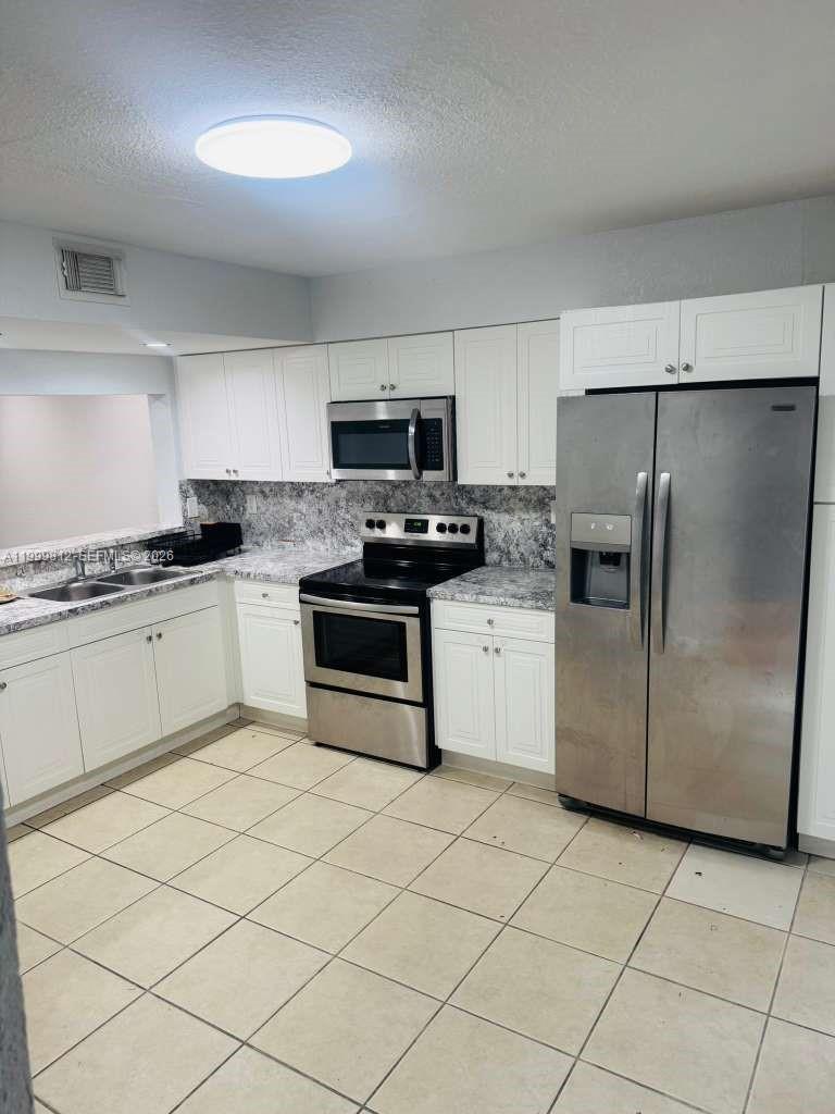 8270 Southwest 149th Court, Unit 10209 Miami, FL 33193 - Photo 7 of 32 a kitchen with granite countertop cabinets stainless steel appliances and a counter space