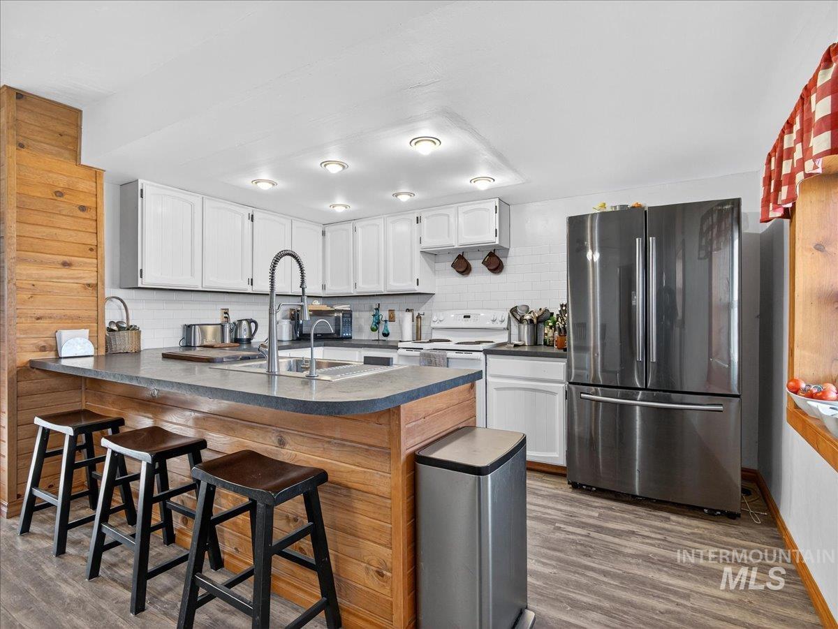 2588 West Sales Yard Road Emmett, ID 83617 - Photo 18 of 49 Kitchen with a peninsula, freestanding refrigerator, dark countertops, a breakfast bar, and white cabinets