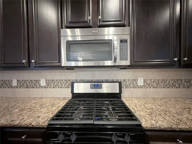a kitchen with granite countertop a stove and a microwave