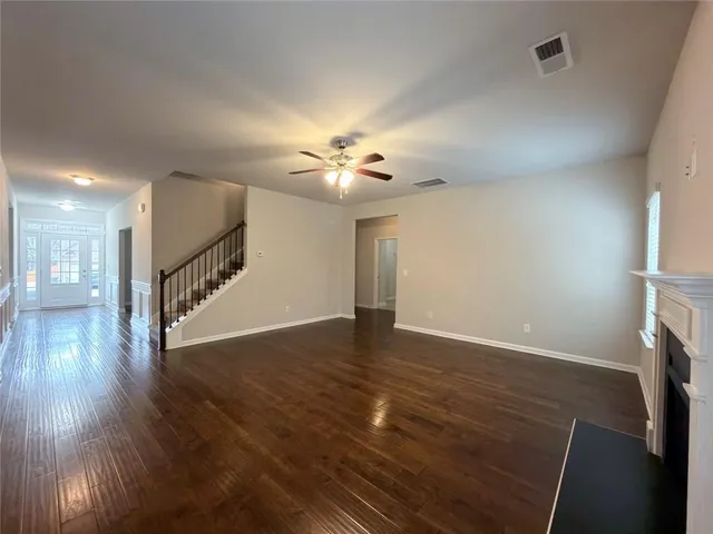 a view of an empty room with wooden floor and a fireplace