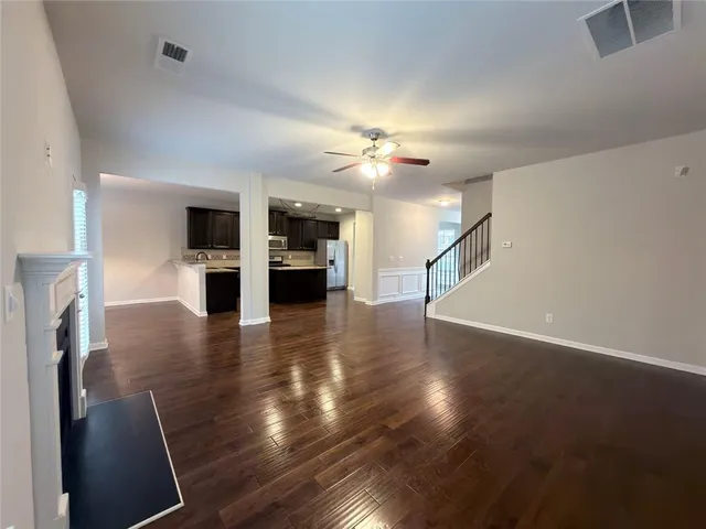 an empty room with wooden floor fireplace and windows