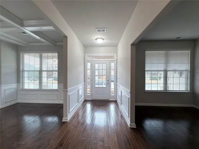 an empty room with wooden floor and windows