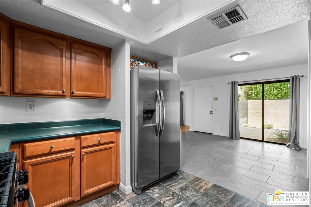 200 East Racquet Club Road, Unit 45 Palm Springs, CA 92262 - Photo 15 of 36 a kitchen with stainless steel appliances granite countertop a refrigerator a sink and dishwasher with wooden cabinets