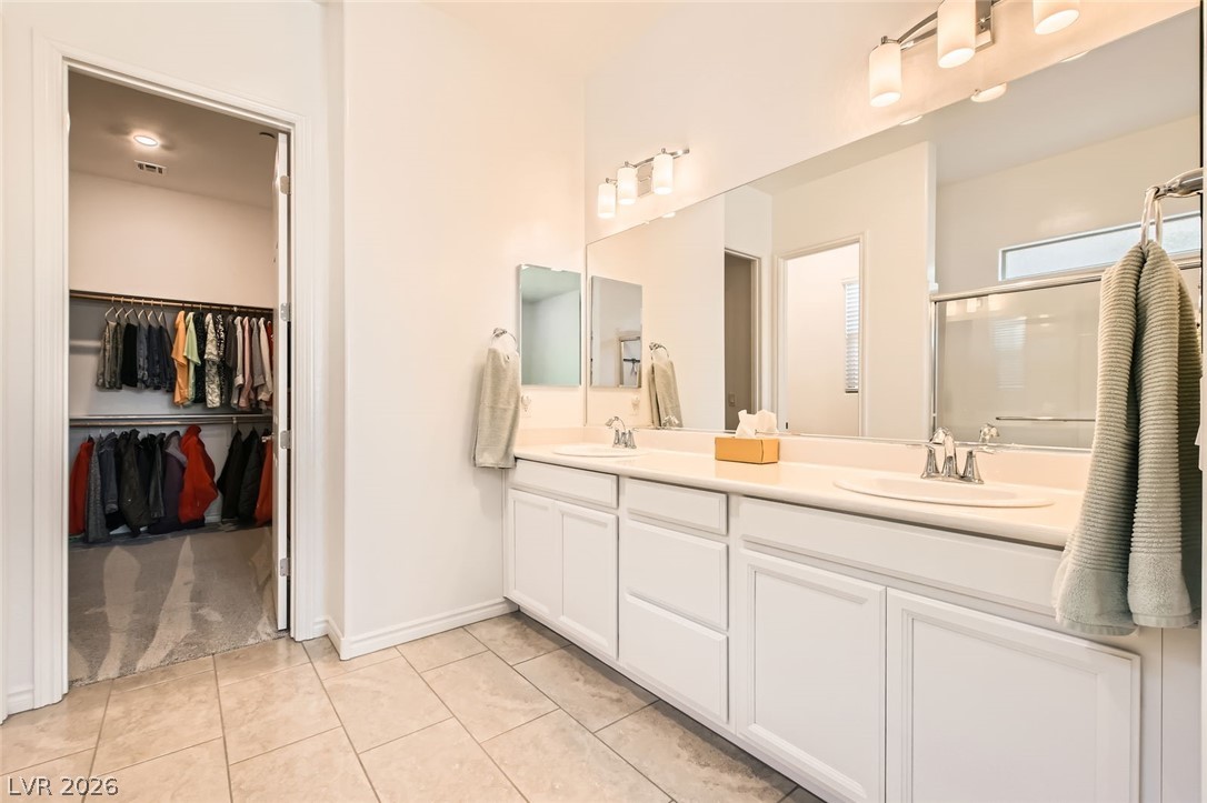 498 Pebble Run Avenue Henderson, NV 89011 - Photo 13 of 47 This primary bathroom offers a dual vanity with ample counter space and an adjacent walk-in closet.