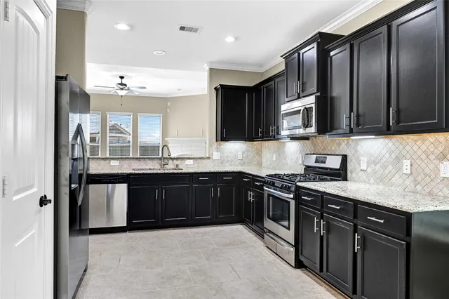 a kitchen with stainless steel appliances granite countertop a stove a sink and a microwave